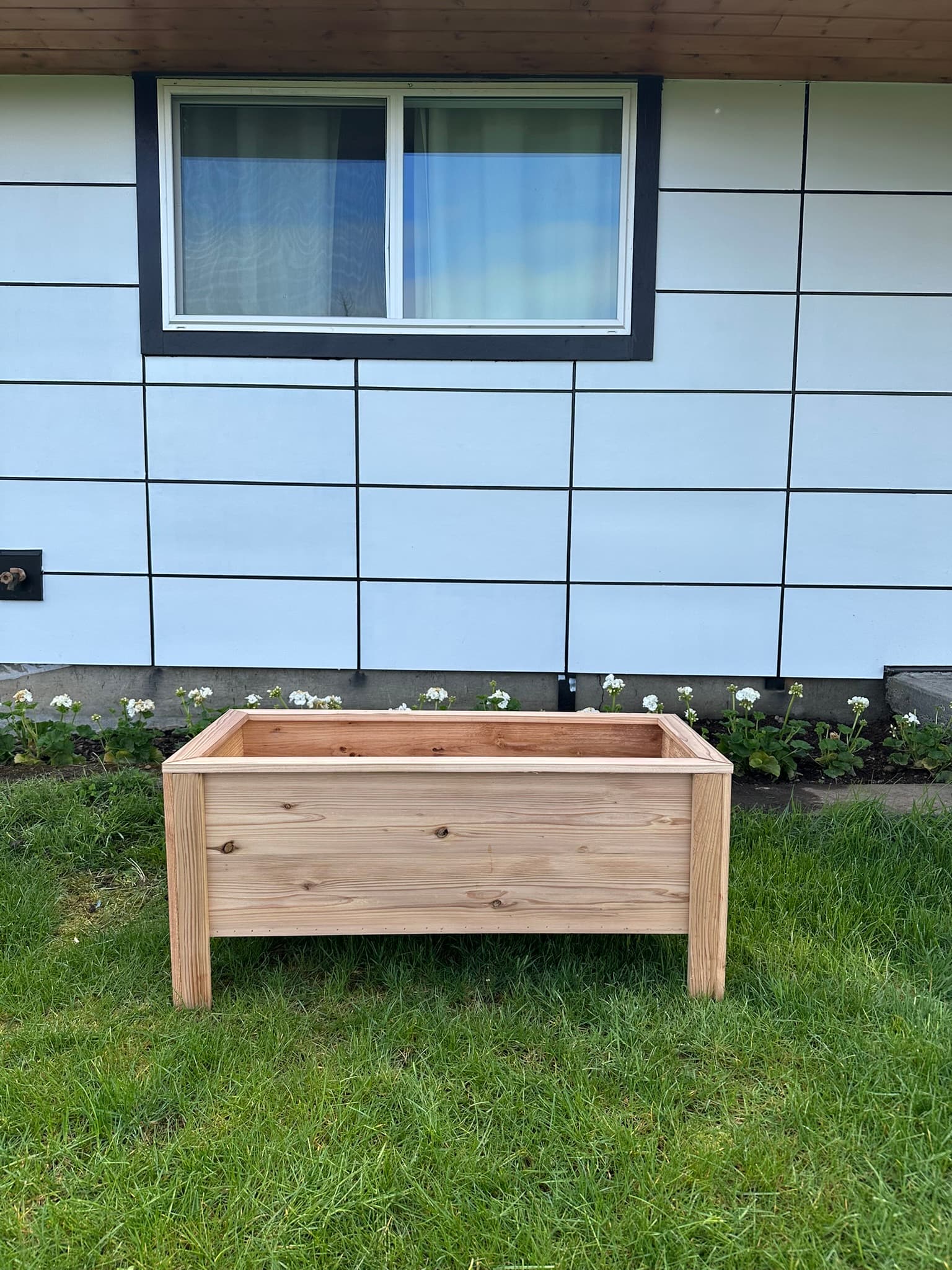 Medium cedar raised garden bed with mid-height legs, front view against siding